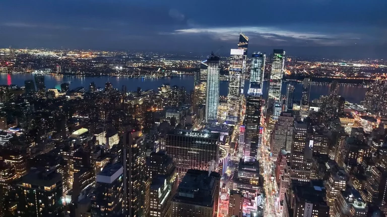 Beleuchtete Skyline von Manhattan bei Nacht von einer Aussichtsplattform
