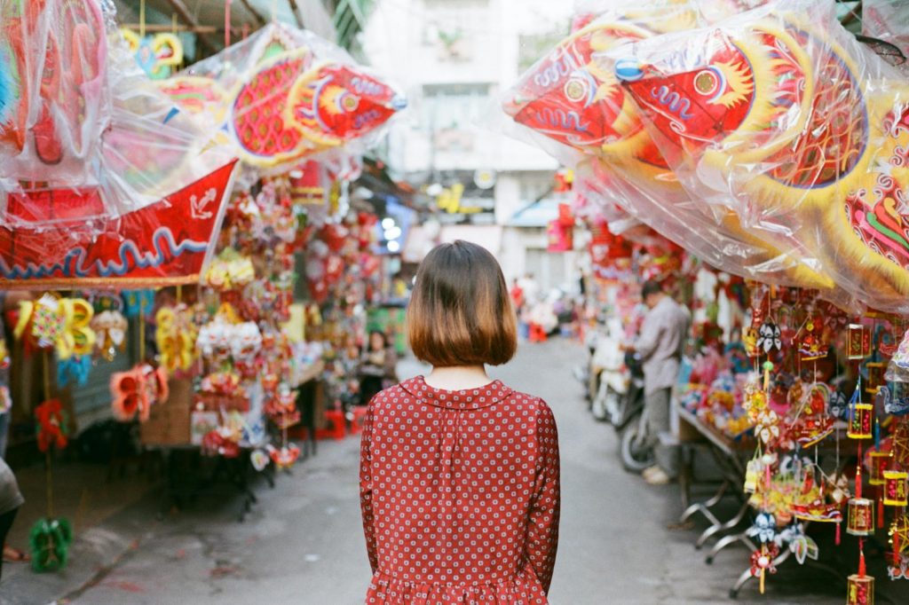 An adult female enjoys colorful decorations at a vibrant street market in Ho Chi Minh City, Vietnam.