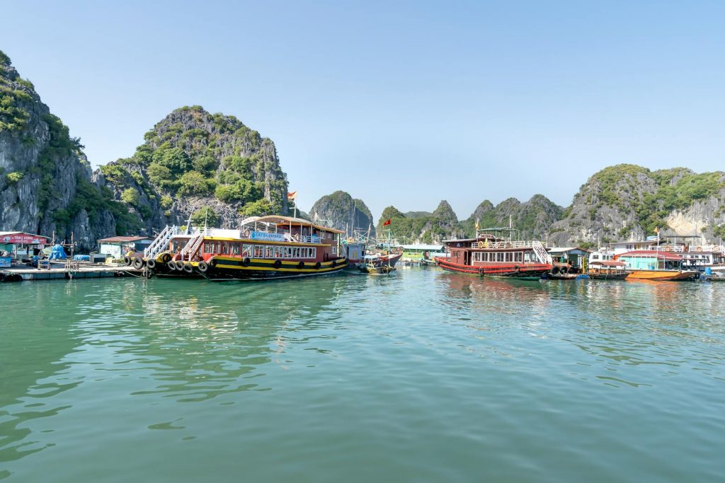 Tourist boats navigate the stunning waters of Ha Long Bay, surrounded by limestone cliffs.