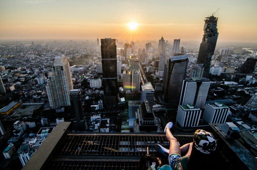 Person sitzt auf einer Kante mit Blick über Bangkok