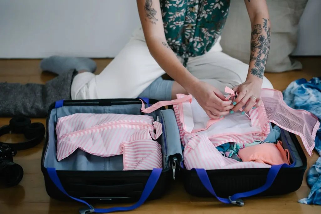 Reisende verschließt einen Packwürfel in einem geöffneten Koffer