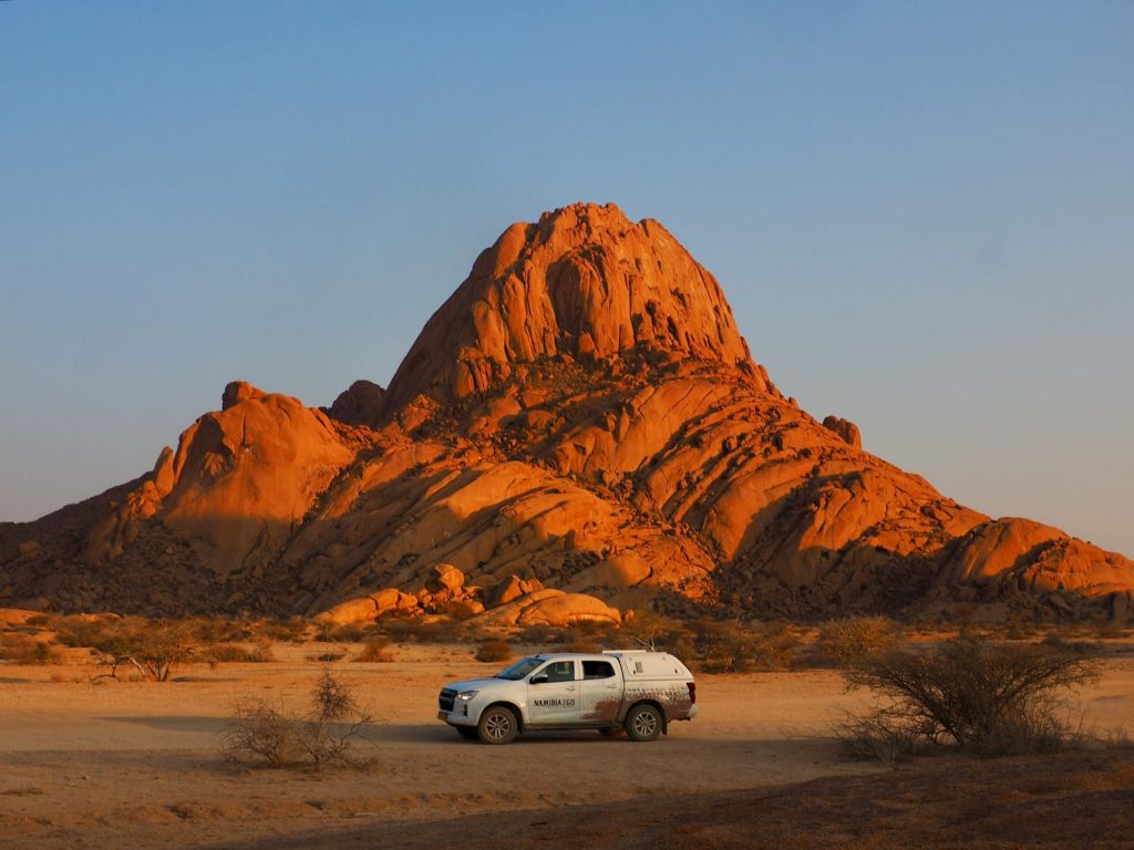 Sonnenuntergang an der Spitzkoppe in Namibia mit Auto im Vordergrund