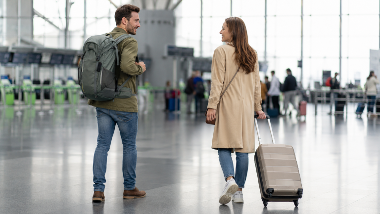 Reisende mit Reiserucksack und Rollkoffer am Flughafen