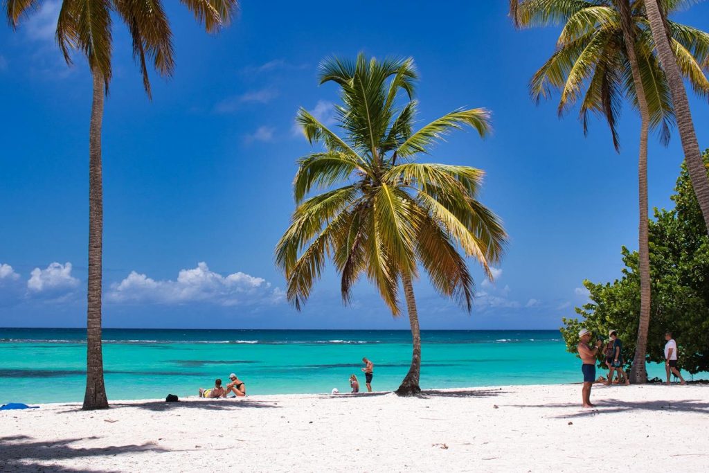 Tropischer Strand mit Palmen und Menschen am Meer