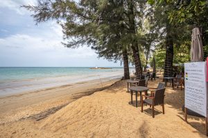 Scenic view of a beachside dining area under trees in Thailand, perfect for a tropical getaway.