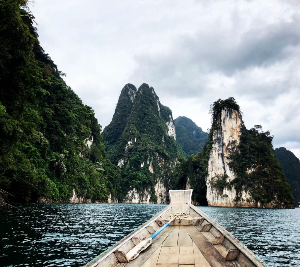 Cheow Lan Lake im Khao Sok Nationalpark mit Kalksteinfelsen und Longtailboot.